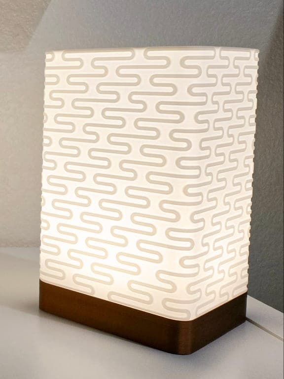 Rectangular table lamp with S-curve lattice pattern glowing white