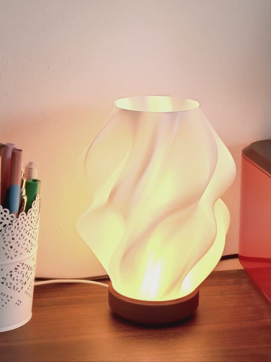 Spiral glow table lamp with warm yellow ambient light on desk